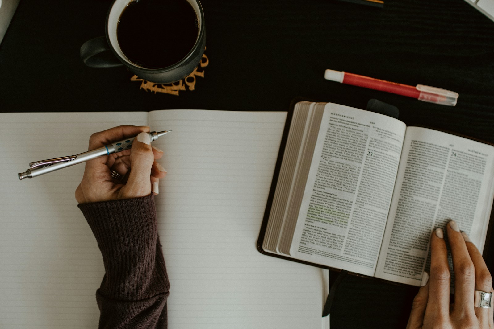 Manos tomando notas junto a una Biblia abierta